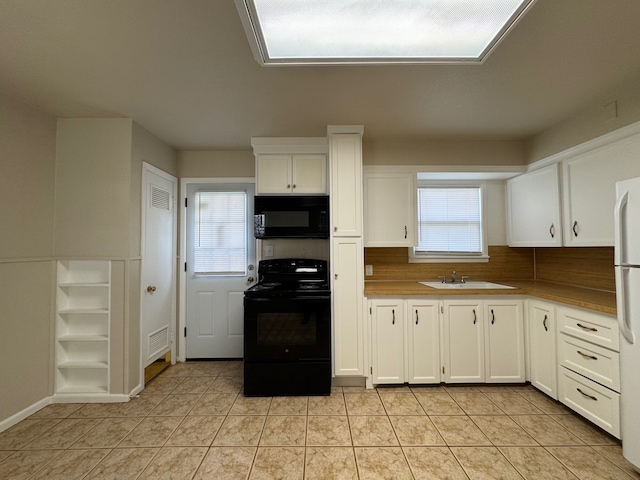 kitchen with visible vents, light tile patterned flooring, a sink, black appliances, and white cabinets