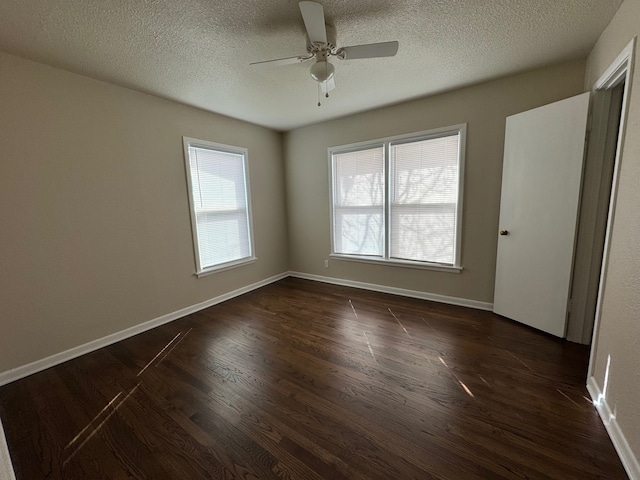 unfurnished bedroom with baseboards, multiple windows, dark wood-type flooring, and a textured ceiling