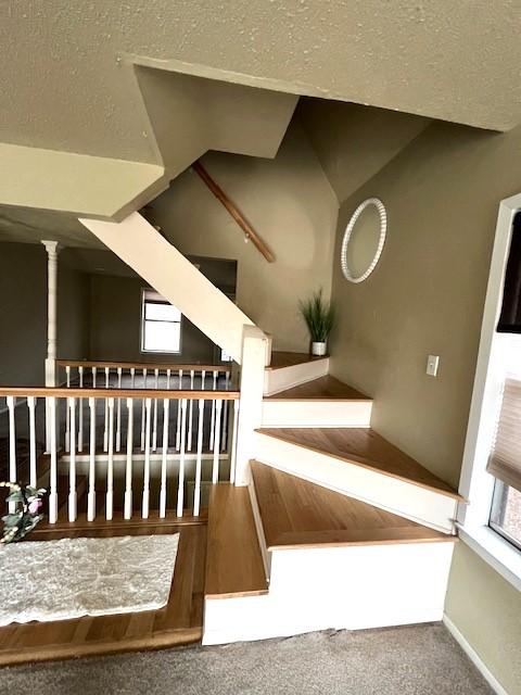 stairs featuring baseboards, a textured ceiling, and carpet flooring