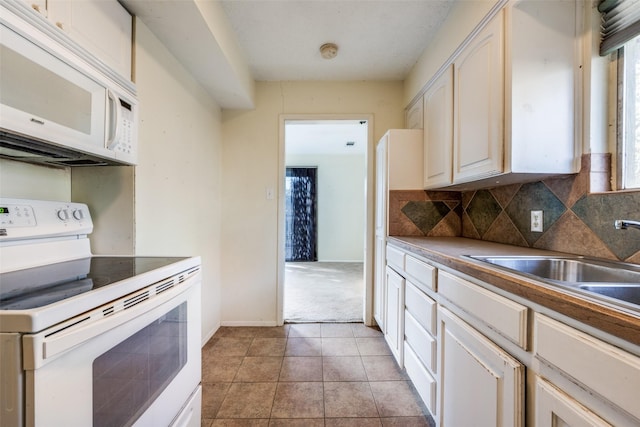 kitchen with a sink, white appliances, light tile patterned flooring, decorative backsplash, and baseboards