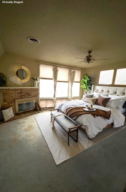 carpeted bedroom with visible vents, a fireplace, a textured ceiling, and ceiling fan