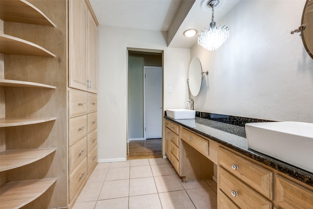 bathroom with tile patterned floors, double vanity, baseboards, and a sink