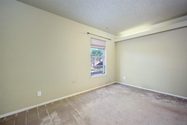 carpeted spare room featuring baseboards and a textured ceiling