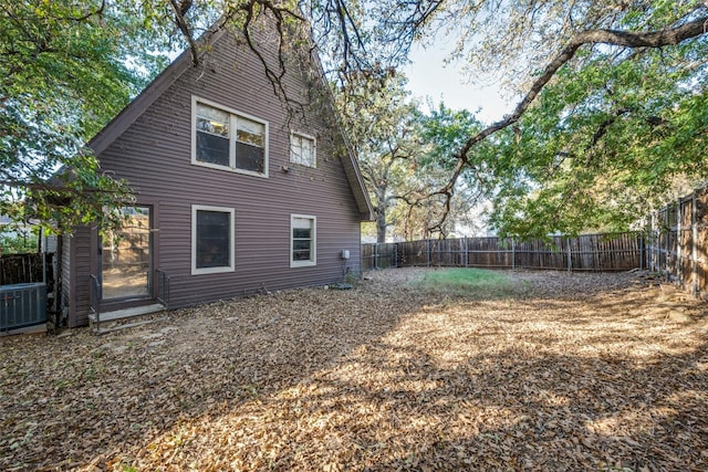 rear view of property featuring a fenced backyard and central AC