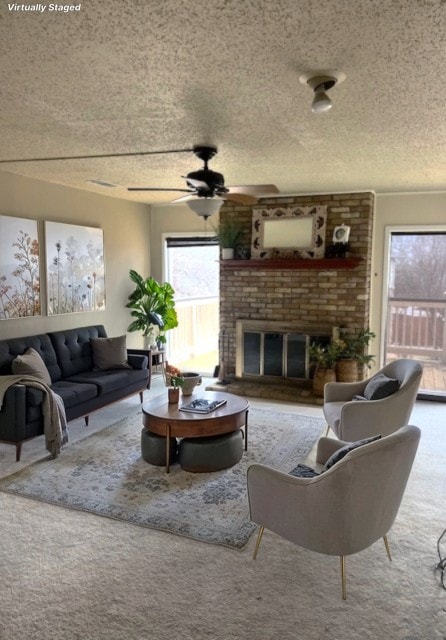 carpeted living room with ceiling fan, a brick fireplace, and a textured ceiling