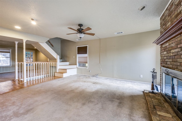 unfurnished living room with visible vents, a textured ceiling, a brick fireplace, and carpet flooring