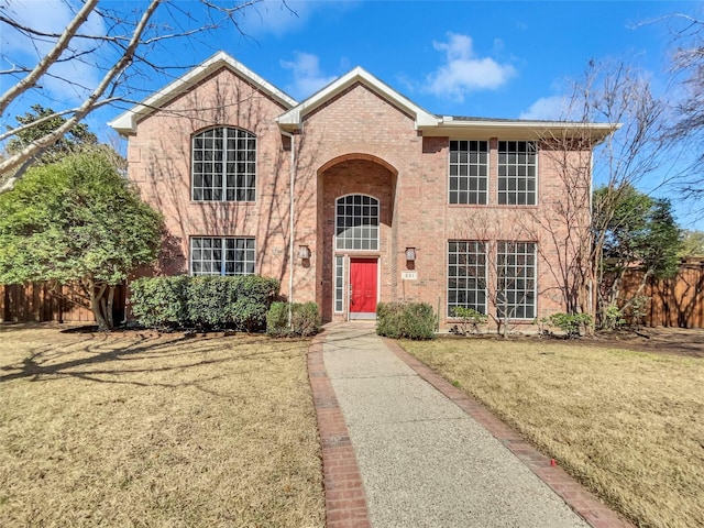 traditional-style house with brick siding, a front lawn, and fence