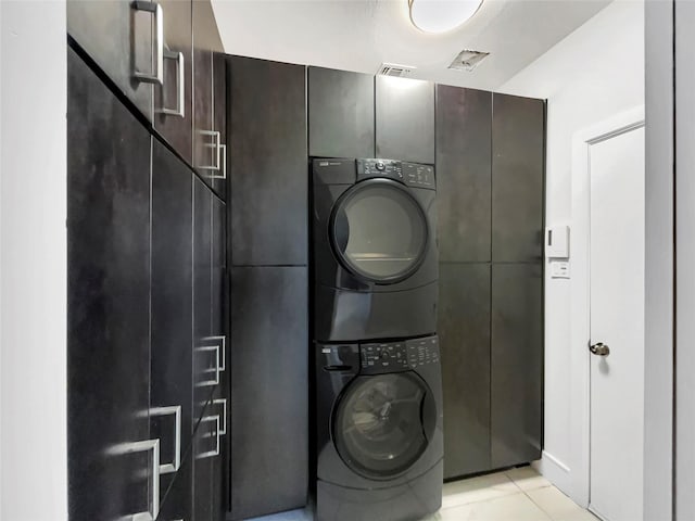 washroom featuring stacked washer / dryer and cabinet space