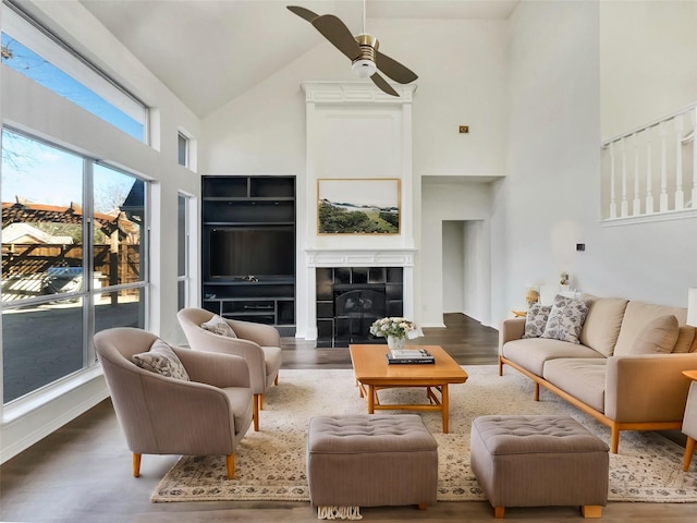 living room featuring a tiled fireplace, high vaulted ceiling, a ceiling fan, and wood finished floors