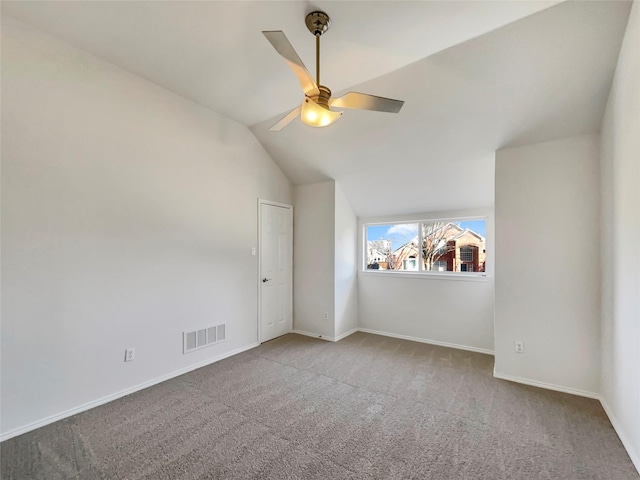 carpeted empty room featuring vaulted ceiling, baseboards, visible vents, and ceiling fan