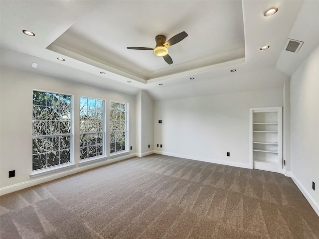 empty room featuring a tray ceiling and baseboards