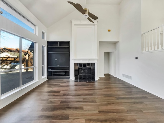 unfurnished living room featuring wood finished floors, visible vents, high vaulted ceiling, a fireplace, and ceiling fan