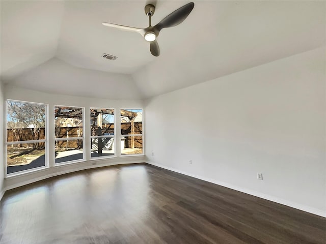 empty room featuring visible vents, baseboards, dark wood finished floors, vaulted ceiling, and a ceiling fan