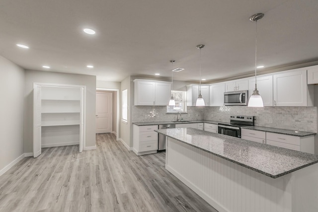 kitchen with stainless steel appliances, a sink, visible vents, light wood-style floors, and decorative backsplash