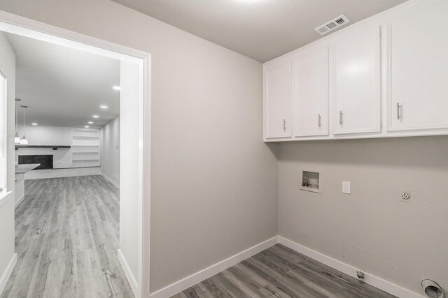 laundry room with hookup for a washing machine, cabinet space, light wood-style flooring, baseboards, and visible vents