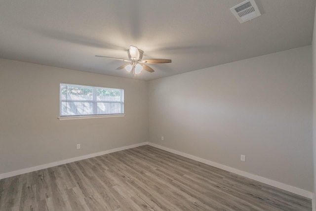 empty room featuring baseboards, wood finished floors, visible vents, and a ceiling fan