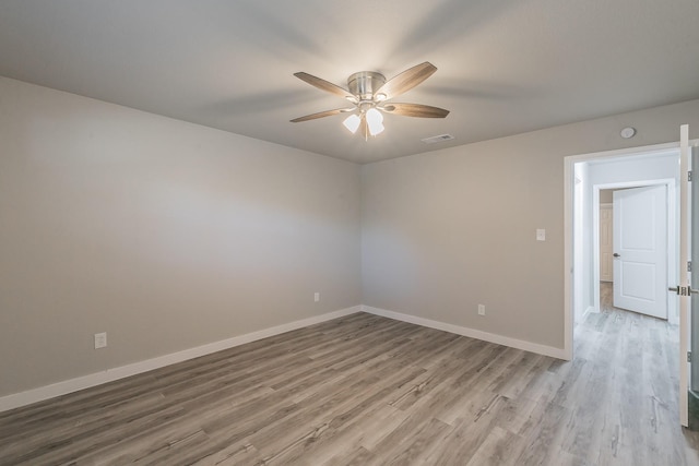 empty room with ceiling fan, baseboards, wood finished floors, and visible vents