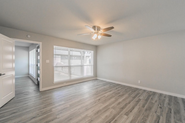 spare room with baseboards, a ceiling fan, and wood finished floors