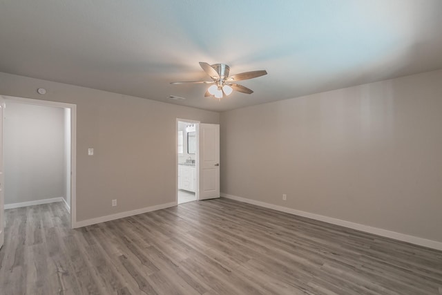 empty room featuring wood finished floors, visible vents, baseboards, and ceiling fan