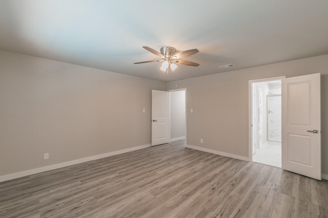 unfurnished bedroom with light wood-style flooring, baseboards, visible vents, ceiling fan, and ensuite bath