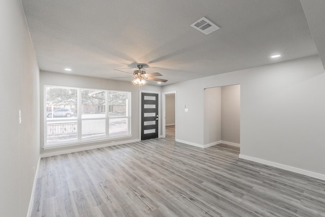 spare room featuring baseboards, a ceiling fan, visible vents, and light wood-type flooring