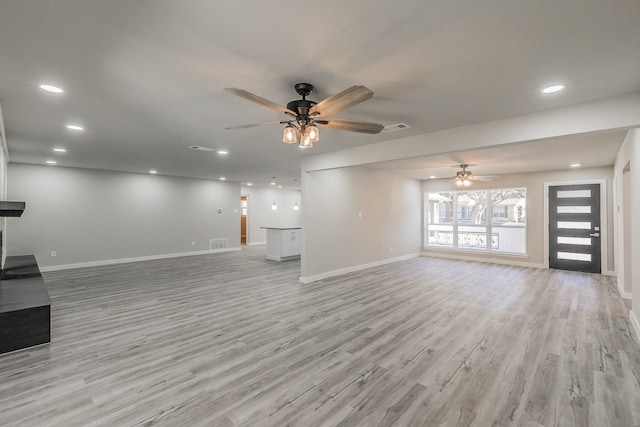 unfurnished living room with light wood finished floors, baseboards, a ceiling fan, and visible vents