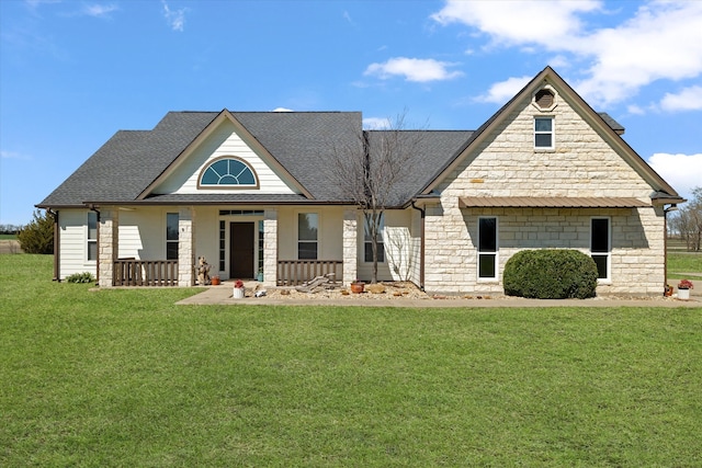 view of front of house with stone siding, a porch, a shingled roof, and a front yard