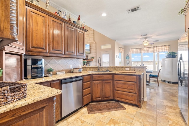 kitchen featuring tasteful backsplash, a peninsula, brown cabinetry, stainless steel appliances, and a sink