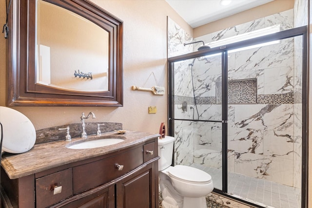 bathroom featuring a marble finish shower, toilet, and vanity