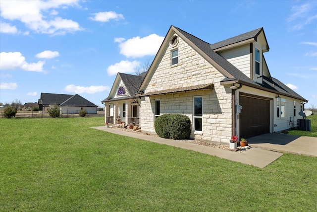 view of side of property with concrete driveway, central AC, roof with shingles, a lawn, and stone siding