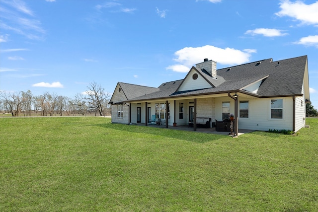 back of house featuring a yard, a patio area, a chimney, and a shingled roof