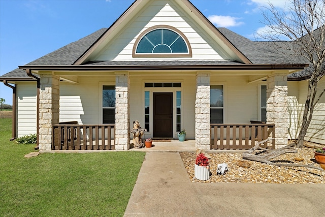 doorway to property featuring covered porch, a shingled roof, and a lawn