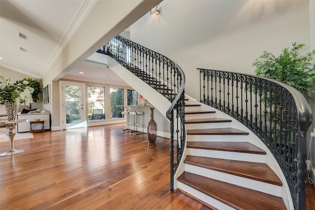 stairway with visible vents, crown molding, baseboards, and wood finished floors