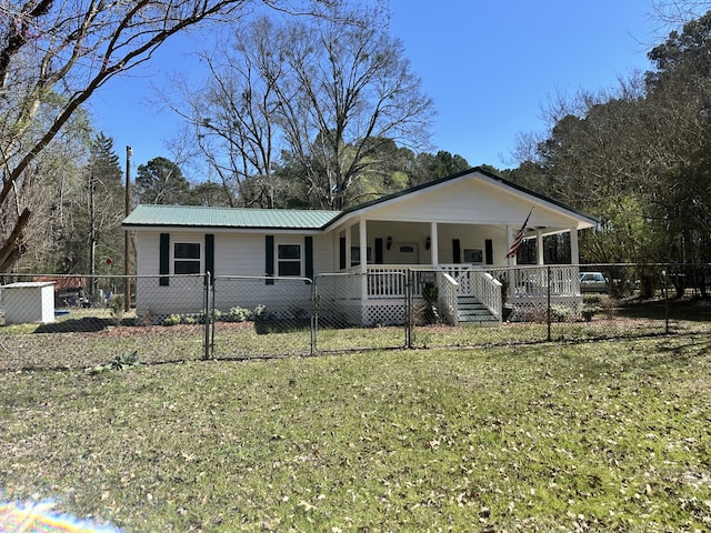 view of front of home with a front lawn, a fenced front yard, covered porch, metal roof, and a gate