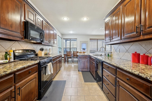 kitchen with light tile patterned floors, light stone countertops, black appliances, and a sink