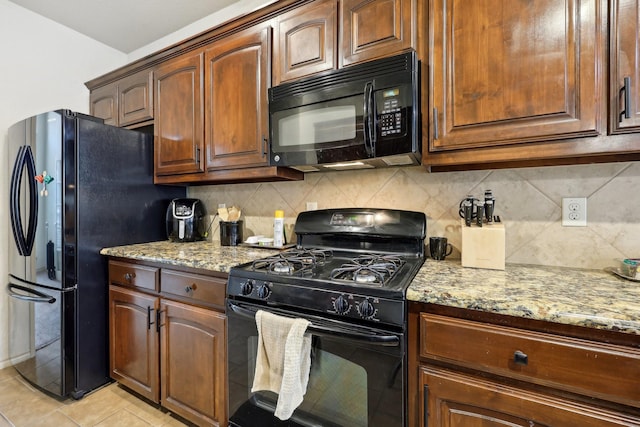 kitchen with light stone counters, backsplash, black appliances, and light tile patterned flooring