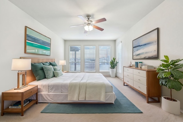 bedroom with a ceiling fan and light colored carpet