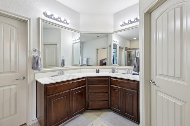 full bath featuring tile patterned flooring, double vanity, a stall shower, and a sink