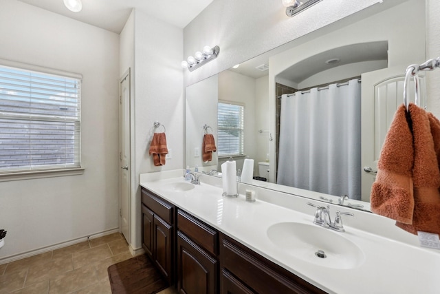 full bathroom with tile patterned flooring, double vanity, baseboards, and a sink