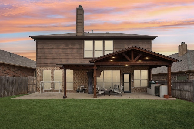 back of house featuring a lawn, a fenced backyard, brick siding, and a patio area