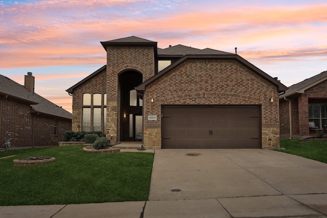 view of front of house with a lawn, driveway, stone siding, a garage, and brick siding