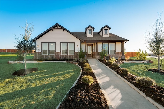 view of front of property with a front yard, fence, and brick siding