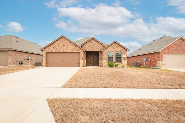 view of front of house with a garage, central air condition unit, brick siding, and driveway