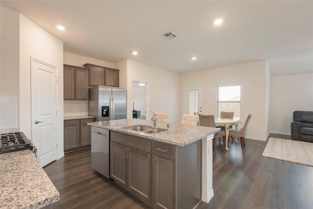 kitchen featuring visible vents, a center island with sink, a sink, tasteful backsplash, and stainless steel appliances