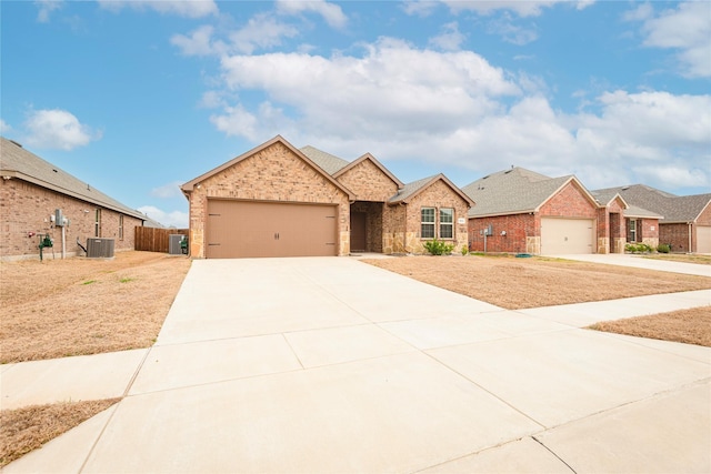 ranch-style home featuring concrete driveway, an attached garage, central AC unit, and brick siding