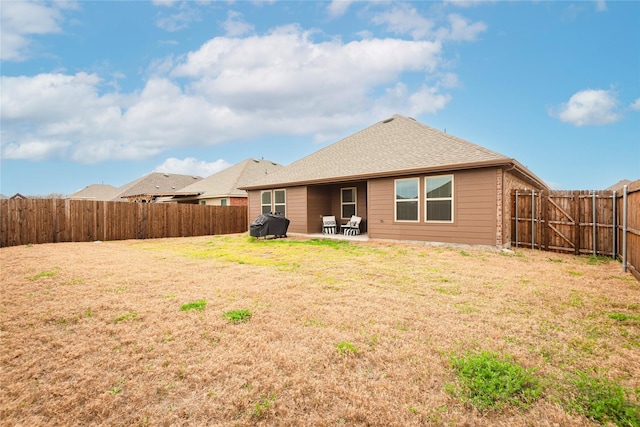 back of property featuring a patio, a yard, a fenced backyard, and roof with shingles