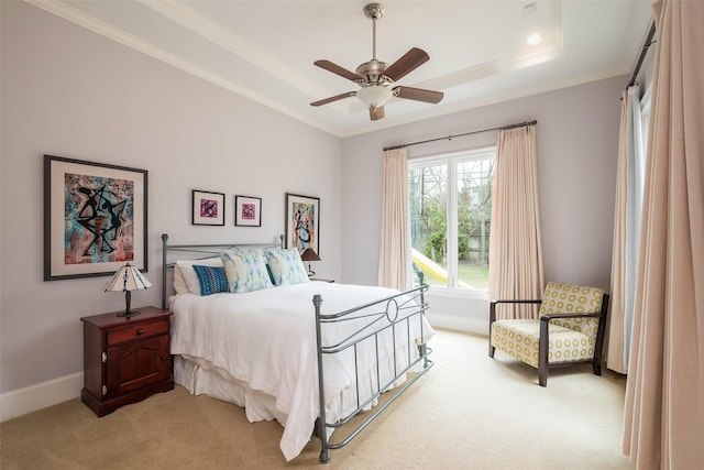 bedroom featuring a ceiling fan, a tray ceiling, crown molding, baseboards, and light colored carpet