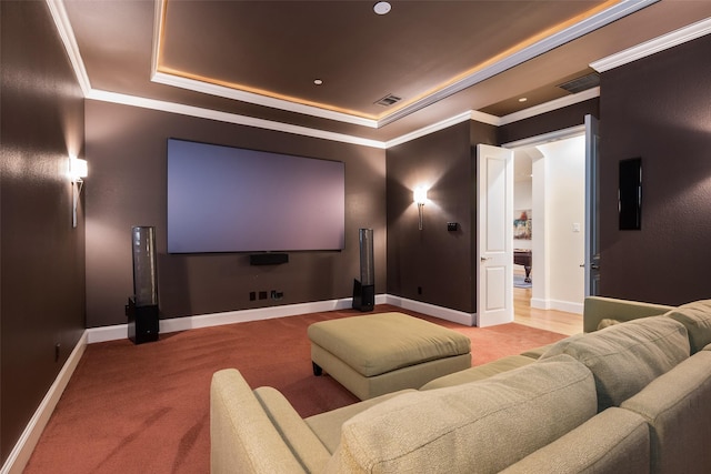 carpeted home theater room with visible vents, baseboards, a tray ceiling, and ornamental molding