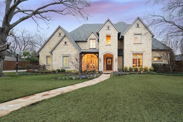 french country home featuring a standing seam roof, fence, a yard, roof with shingles, and metal roof