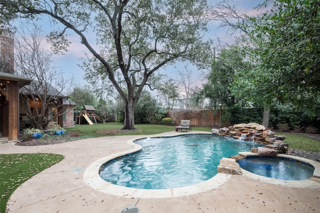 view of pool with a pool with connected hot tub, a playground, fence, a yard, and a patio